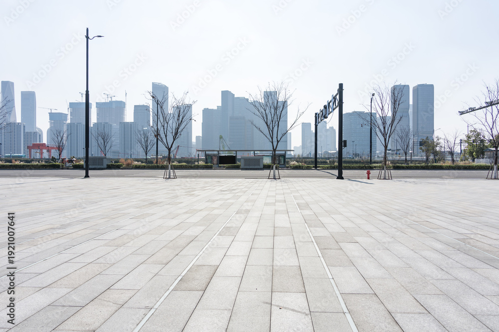 Fototapeta premium Empty urban plaza with paved ground and modern high-rise buildings in the background