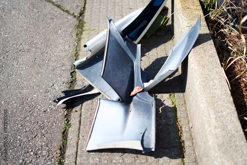 Fotografía Broken plastic car bumper parts on sidewalk