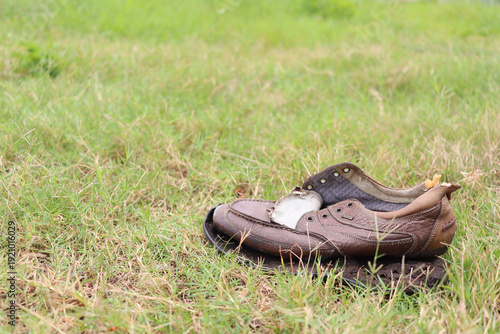 single old brown leather shoe discarded on the lawn; the concept of uselessness and discarding.