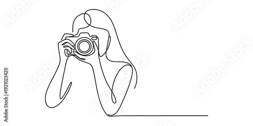 Continuous line drawing of a woman photographer holding a professional camera to her eye.