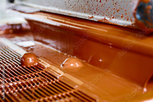 Candy enrobing process showcasing curtain coating technique with chocolate flowing in a manufacturing setting