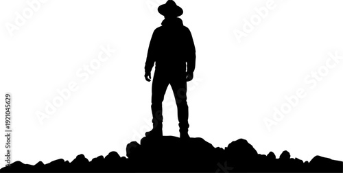 Man in a hat silhouette standing on a rocky ridge