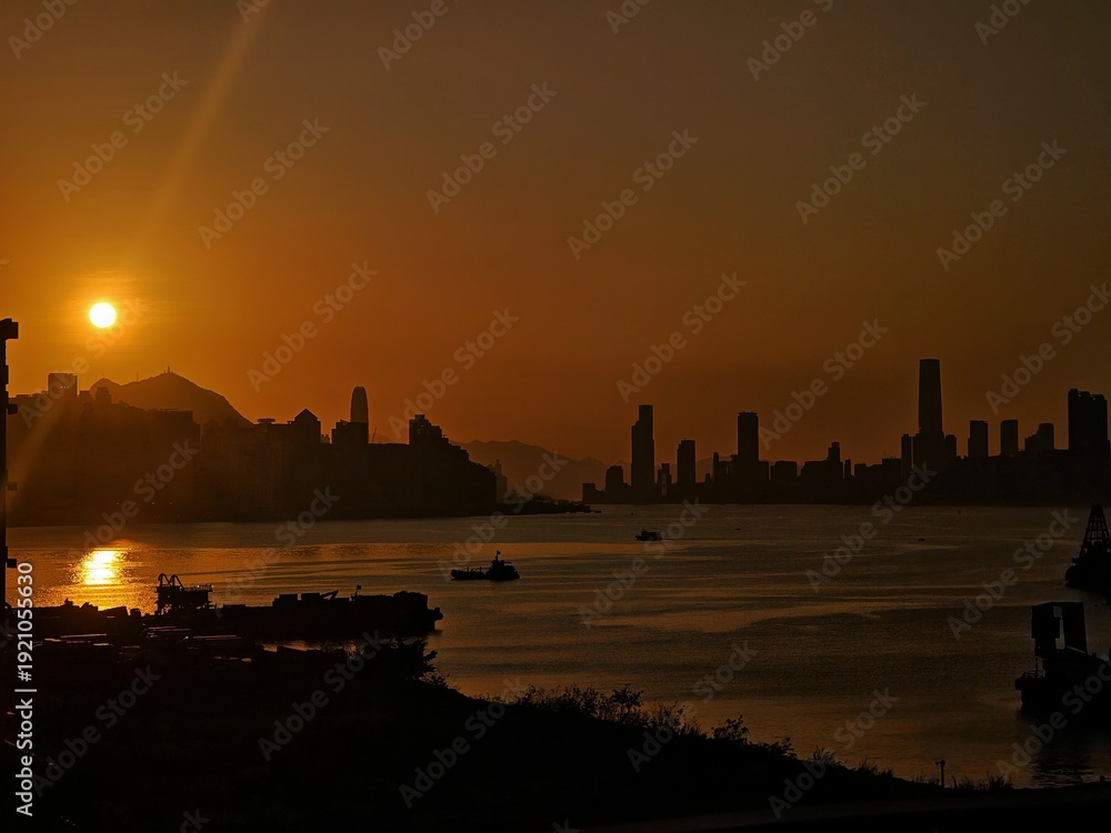 Fototapeta premium A dramatic sunrise illuminates a towering cityscape reflected in a