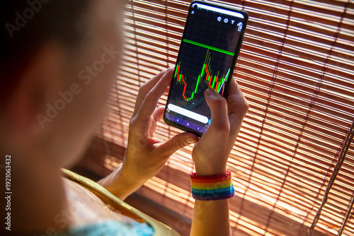 Fotografie Queer person investing money with smartphone app.