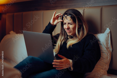 Foto Woman Squinting and Lifting Her Glasses to Read on the Screen