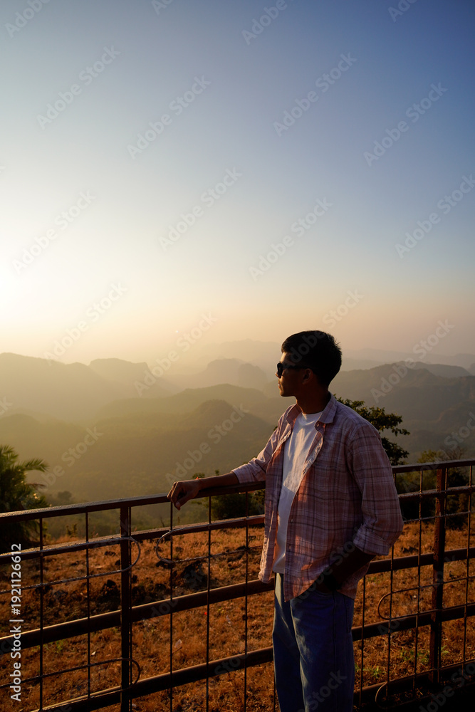 Fototapeta premium Man Gaze Serene Mountain Vista At Sunset With Warm Hues Over Landscape