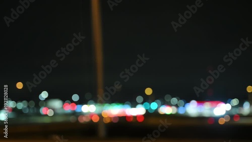 Blurred side View of car driving on a highway at night with glowing buildings. Scene shows urban transportation, night traffic. 