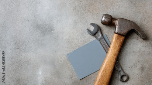 Hammer and a wrench are on a grey surface