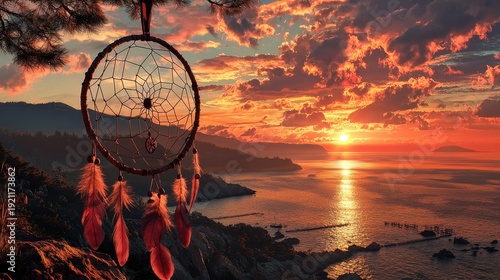 A dreamcatcher hangs over a body of water with a beautiful sunset in the background. The dreamcatcher is red and gold, and it is suspended from a tree branch. The scene is serene and peaceful