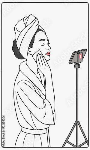 Woman in bathrobe and towel on head applying skincare in front of a phone on a tripod.