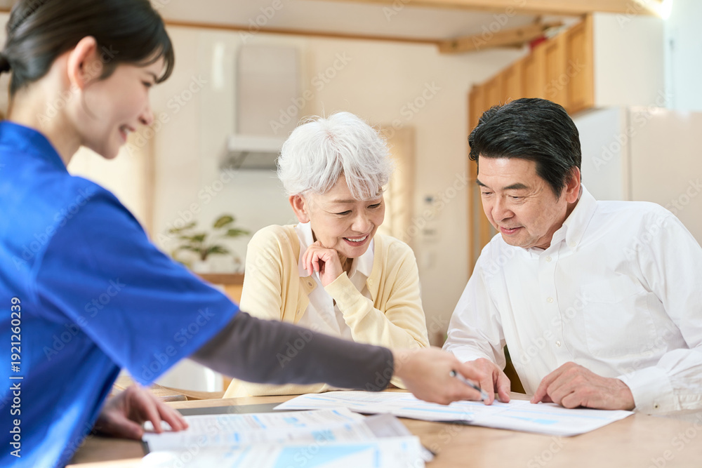 Obraz premium 訪問介護でプランの説明を聞くシニア夫婦
