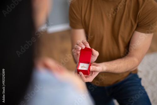 Foto Man proposing marriage holding engagement ring in red box