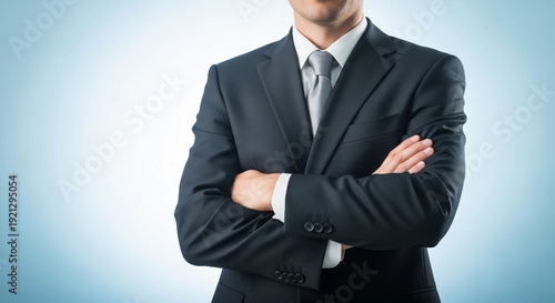 A confident businessman stands with arms crossed in a professional pose against a blurred blue background