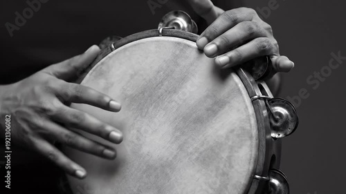 Close Up of Dark Skinned Hands Playing Tambourine in a Black and White Composition