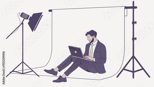Man working on laptop in a photo studio setup.