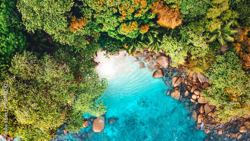Aerial view of a secluded cove in Anse Lazio Bay, Praslin Island, Seychelles, with pristine turquoise waters, lush tropical jungle, and iconic granite boulders. A true Indian Ocean paradise.