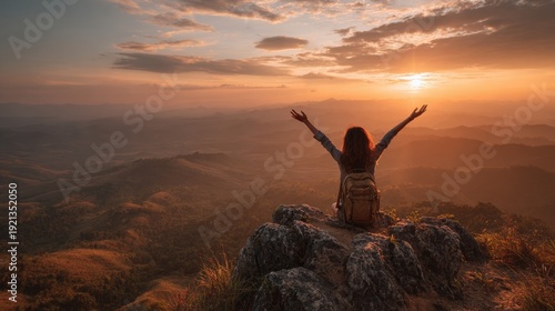 Woman with arms raised celebrating mountain sunset