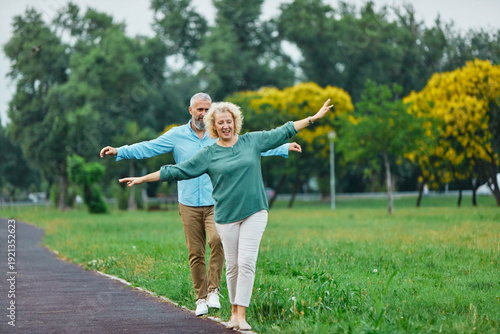 Quadro su tela Happy active mid aged adult couple having fun walking and balancing and bonding