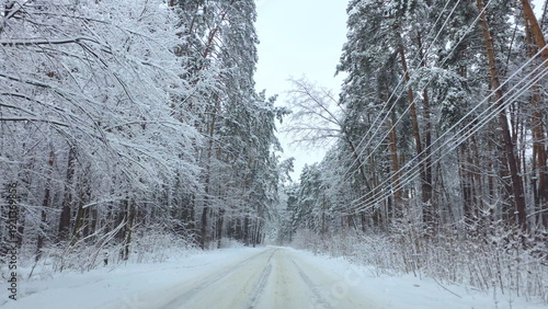 Canvas Print Car driving along snowy forest road in winter landscape, Winter journey through