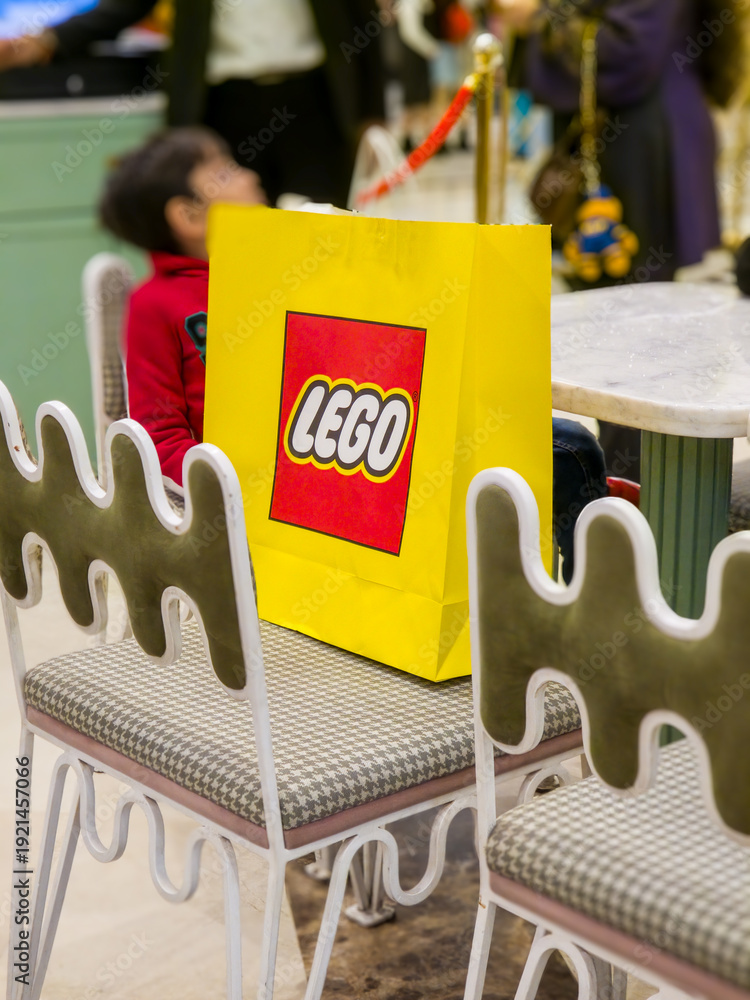 Fototapeta premium Customers carrying the iconic yellow and red themed LEGO bag from India's first store in ambience mall showing the popularity of this toy