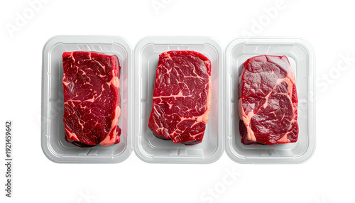 Three raw, uncooked steaks in plastic containers, overhead view