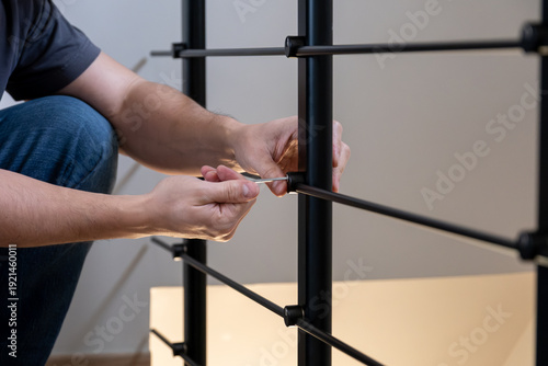 Foto Man's hands installing components of a modern black metal balustrade with a scre