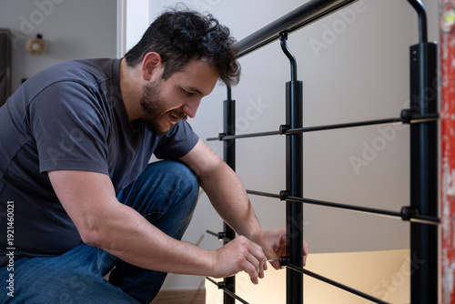 Man installing new black metal railing for home renovation using a tool