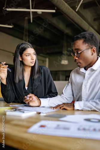 Business meeting between colleagues discussing project plans and strategies at a modern office surrounded by documents with graphics
