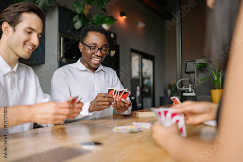 Friends enjoy a spirited card game at a cozy office during a sunny afternoon gathering