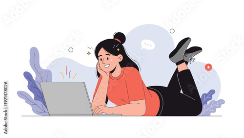 Young woman lies comfortably on her stomach on the floor while using her laptop with a happy smile against a creative abstract background.