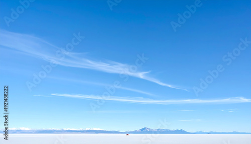 Expansive blue sky over a flat white landscape with distant mountains