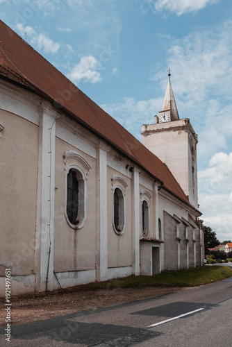 Historic Church of St. Michael the Archangel with Gothic Tower and Baroque Architecture in Dolni Vestonice under summer blue sky