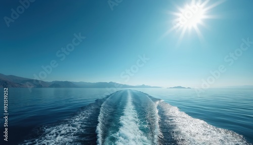 Boat wake on calm ocean water under bright sun and clear blue sky. Mountains visible on distant island shore. Peaceful travel and scenic seascape.