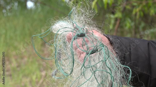 Male hands doing fishing with a rough old net. Fisherman's hand in a fishing net from close range. Close-Up hands of Fisherman Pulling The Fish Net.
