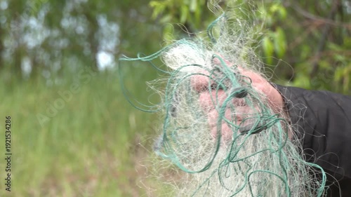 Male hands doing fishing with a rough old net. Fisherman's hand in a fishing net from close range. Close-Up hands of Fisherman Pulling The Fish Net.

