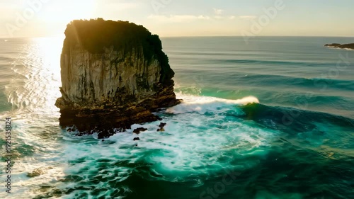 Rocky coastal formation surrounded by turquoise waves and sunlight reflecting on the ocean surface, showcasing the natural beauty of the seaside landscape