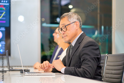 Asian senior businessman working in meeting room with laptop for discussing with team by data information in screen.