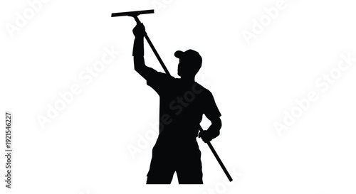 Silhouetted window cleaner reaching upwards with a squeegee and handle