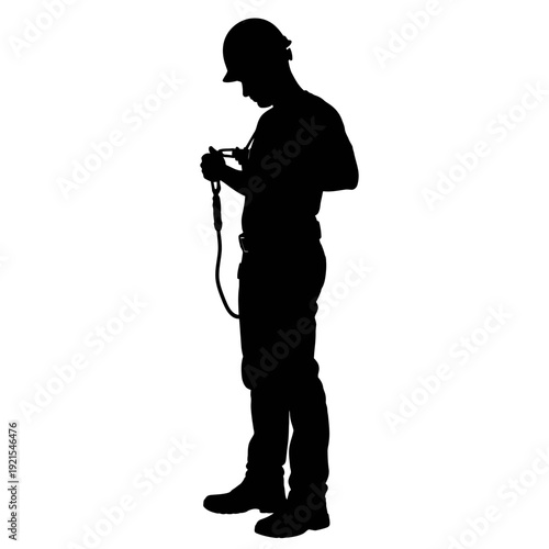 Silhouette of a construction worker inspecting safety harness equipment.