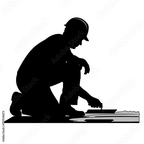 Silhouette of a construction worker kneeling and working on a project.