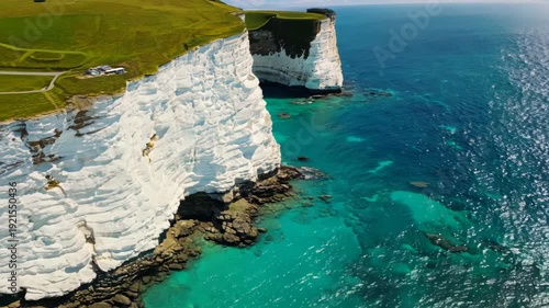 Stunning aerial view of white chalk cliffs meeting turquoise ocean waters, showcasing the natural beauty of coastal landscapes in a serene environment