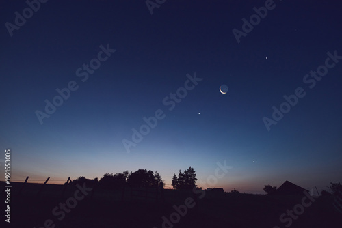 Morning old Moon with stars, planets and rural countryside tree silhouettes.