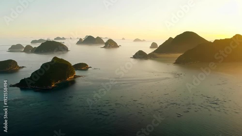 Aerial view of serene coastal landscape featuring rocky islands and calm waters during sunset, showcasing the gradual transition of light and shadow across the scene