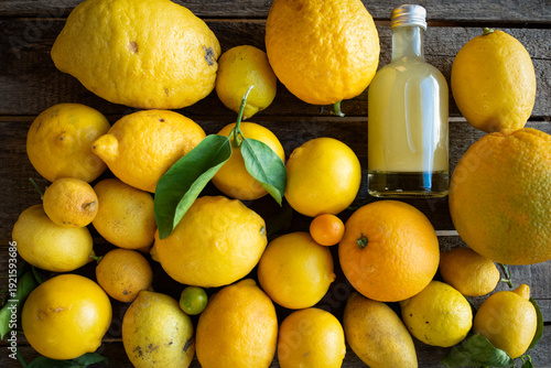 Foto Various lemons with small bottle of limoncello liqueur on dark vintage wood