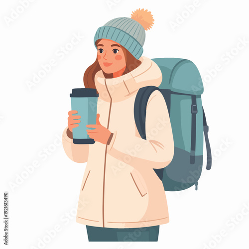 Young woman in winter attire holding coffee while hiking with a backpack on a cold day