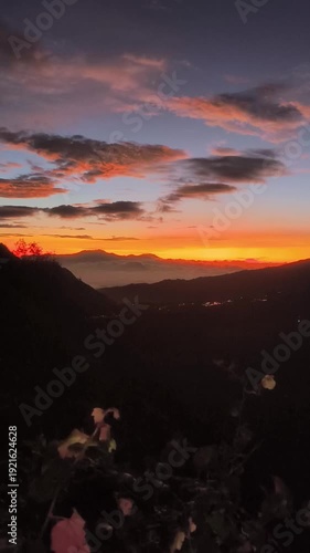 Cinematic 4K sunrise over misty mountains and orange glowing sky in a tropical valley.