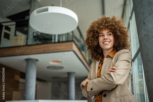 Obraz na plátně Businesswoman with afro hair confidently smiling in modern office