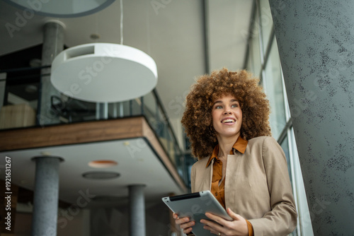 Photos Businesswoman holding tablet looking away in modern office