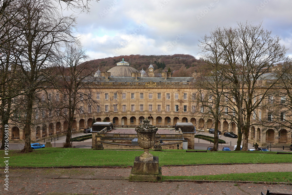 Obraz premium Historic Buxton Crescent; iconic Georgian architecture and luxury thermal spa building in Buxton, Derbyshire with The Slopes garden in foreground, Peak District, England