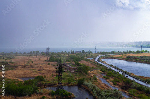 Rainstorm over lake and industrial cityscape